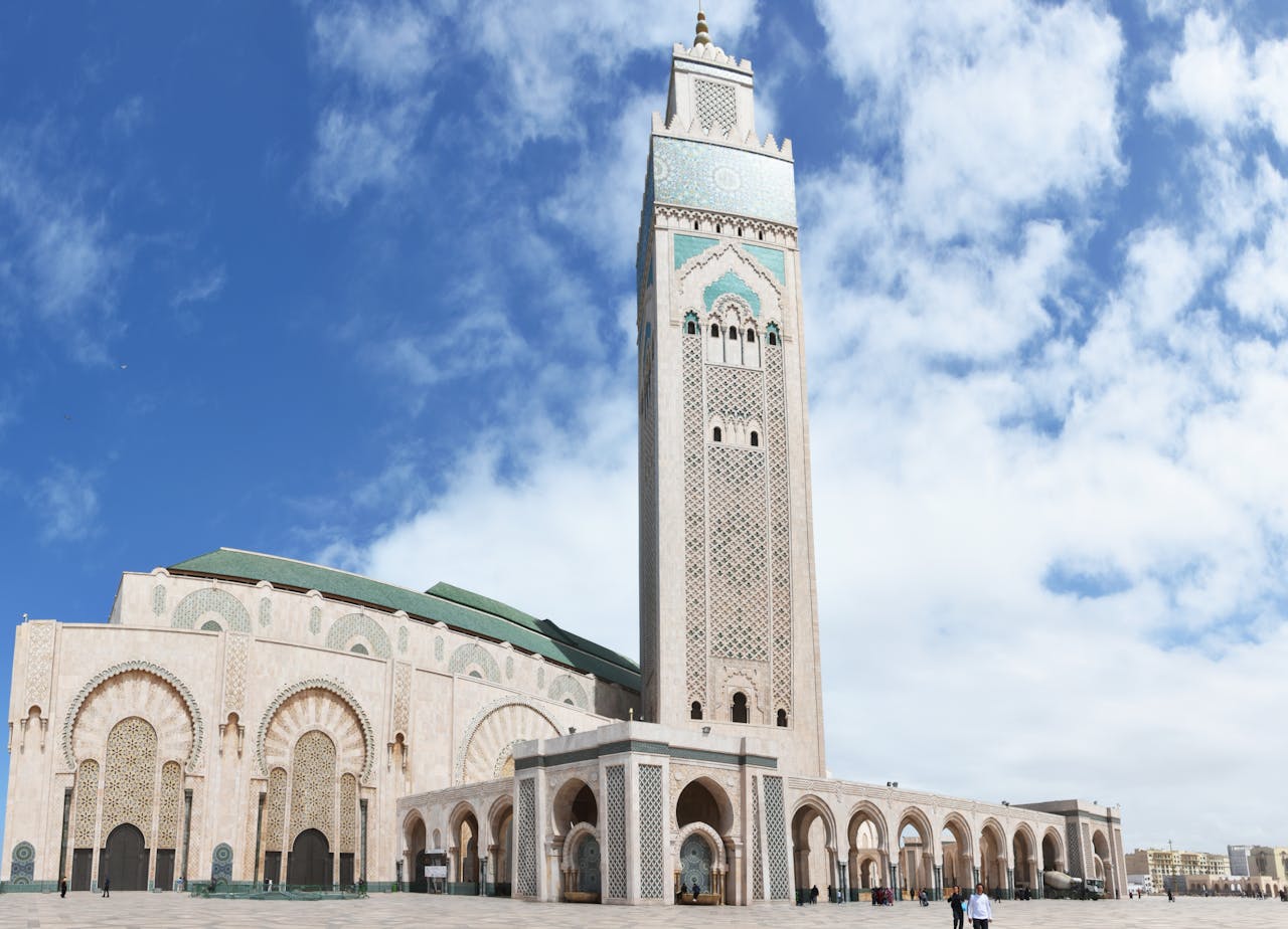 Beautiful low angle view of Hassan II Mosque in Casablanca showcasing its iconic minaret under a blue sky.